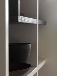 two black bowls are sitting on top of the shelves in this room, and one is empty