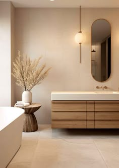 a bathroom with a sink, mirror and bathtub next to a vase filled with flowers