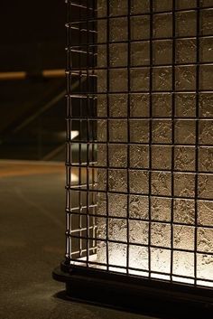 the light is shining on the side of a metal caged structure in the dark