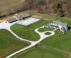 an aerial view of a large white house in the middle of a lush green field