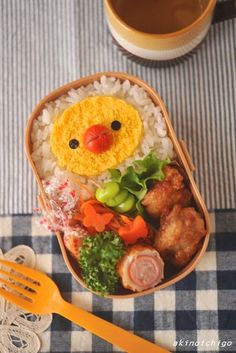 a bento box filled with rice, meats and veggies next to a cup of coffee