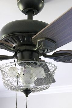 a ceiling fan with a caged light fixture hanging from it's center blade