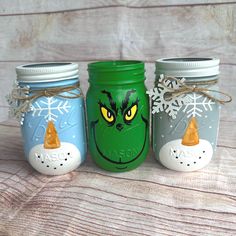 three painted mason jars with snowflakes and grin - face faces on the lids