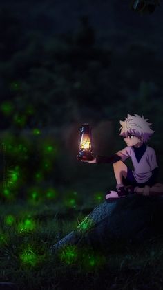 a person sitting on top of a rock holding a lantern in their hand at night