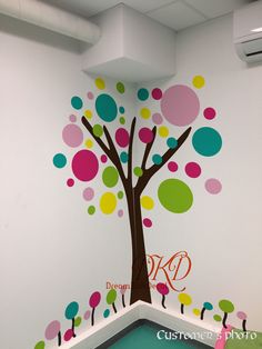 a colorful tree painted on the wall in an office space with polka dot decals