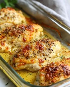 three pieces of chicken in a casserole dish with parsley on the side