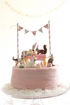 a pink cake topped with lots of animals on top of it