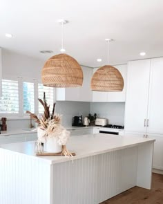 a kitchen with white cabinets and two hanging baskets above the countertop, along with an island in the middle