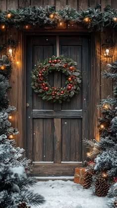 a christmas wreath hanging on the front door of a house with lit garland and pine cones