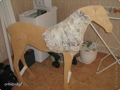 a horse made out of toilet paper sitting on top of a floor next to a trash can