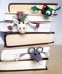 three crocheted animals are sitting on top of books