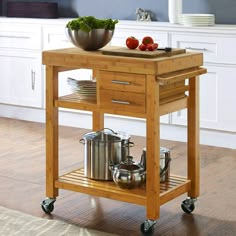 a kitchen island cart with pots and pans on it in the middle of a room