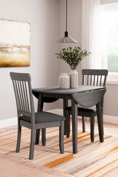 a dining room table with two chairs and a rug on the floor in front of it