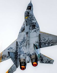 a fighter jet flying through the sky with camouflage paint on it's wings and nose