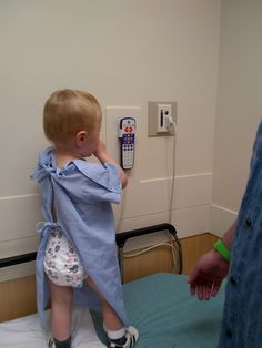 a small child standing on top of a bed next to a wall mounted remote control