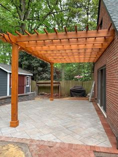 an outdoor patio with a pergolated roof and brick paversed flooring