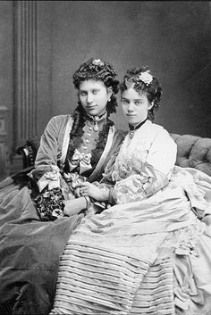 two women sitting next to each other on a bed