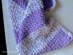 a purple and white crocheted dish cloth on top of a counter next to an oven mitt