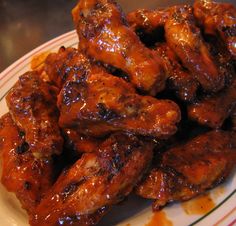 a white plate topped with chicken wings covered in bbq sauce on top of a table