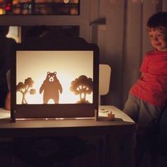 a young boy sitting in front of a computer screen with a bear cut out on it