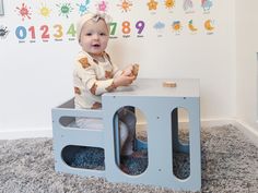 a baby sitting on top of a toy box