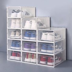 several clear bins filled with shoes on top of a gray floor next to a wall