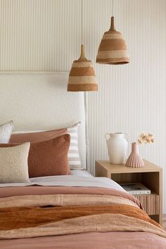 a bed with two lamps above it and some pillows on the side table next to it