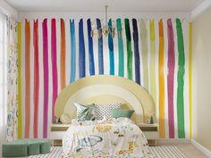 a bedroom with colorful stripes painted on the wall and bed in front of it,