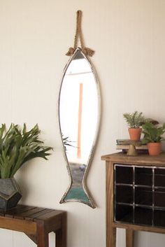 a mirror hanging on the wall next to a wooden table with potted plants in it