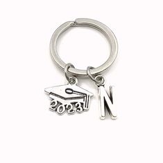 a metal keychain with a graduation cap and the word n on it's side