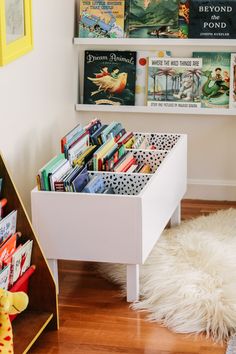 there is a book shelf with books on it and a white rug in the corner