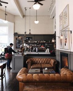 a man standing in front of a bar with leather couches and coffee tables next to it