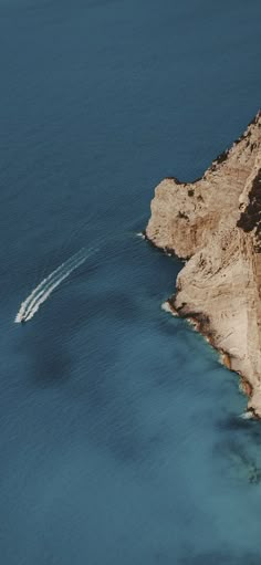 a boat is in the water near some cliffs