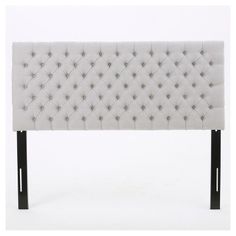 an upholstered headboard with metal legs and buttons on the back, against a white background