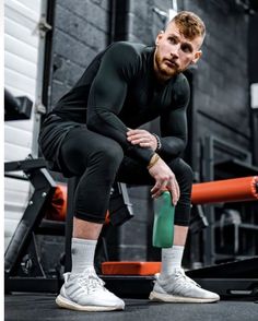 a man squatting on the ground holding a green object