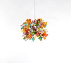 a multicolored glass chandelier hanging from a metal hook on a white wall