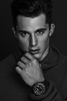 a young man with a watch on his wrist looking at the camera while posing for a black and white photo