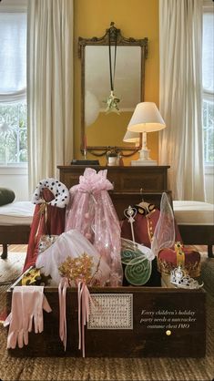 a trunk filled with assorted items in front of a mirror on a table next to a lamp