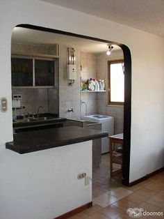 a kitchen that has a sink and a mirror in the middle of it with an open door leading to another room