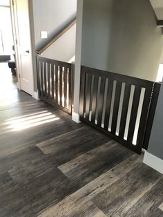 an empty room with hard wood floors and gray walls, along with a stair case