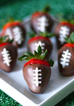 chocolate covered strawberries with white stitching on them are arranged in a square plate