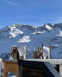 two wine glasses sitting on top of a table in front of a snow covered mountain