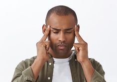 a man is holding his hands to his ears while looking down at the ground with one hand on his head