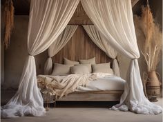 a canopy bed with white drapes and pillows