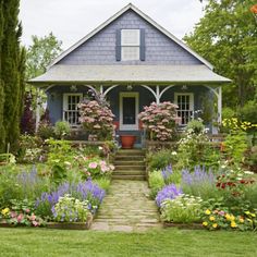 a blue house surrounded by flowers and trees