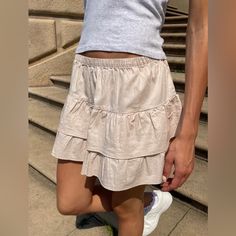 Flowy Tiered Mini Skirt With A Stretchy Waist Line And Ruffle Seams. Fabrics: 100% Cotton Measurements: 13" (33 Cm) Length, 13" (33 Cm) Waist (Stretches) Made In: China Casual Short Mini Skirt For Day Out, Casual Skirted Shorts For Day Out, Casual Tiered Mini Skirt For Summer, Casual Mini Skirt For Summer, Beige Flowy Tiered Mini Skirt, Flowy Beige Tiered Mini Skirt, Beige Ruffled Skirt For Day Out, Casual Skirted Skort For Day Out, Casual Mini Skort With Ruffled Detail