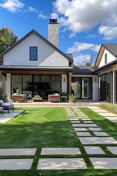 Modern home with large patio area, stylish outdoor furniture, and neatly manicured lawn with stepping stones. Grass Patio Ideas Outdoor Living, Turf Ideas Backyard, Backyards With Turf, Patio And Grass Garden Ideas, Faux Grass Backyard, Artificial Grass Backyard Ideas Design, Turf Patio Ideas, Low Maintenance Backyard Ideas, Artificial Grass Backyard Ideas