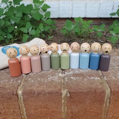 a group of small wooden pegs sitting on top of a brick wall next to green plants