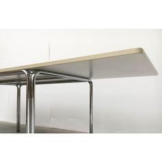 a table with two metal legs and a white wall in the back ground behind it