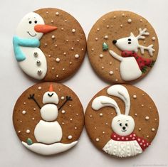 four decorated cookies with frosting on top of each cookie, one has a snowman and the other is a polar bear